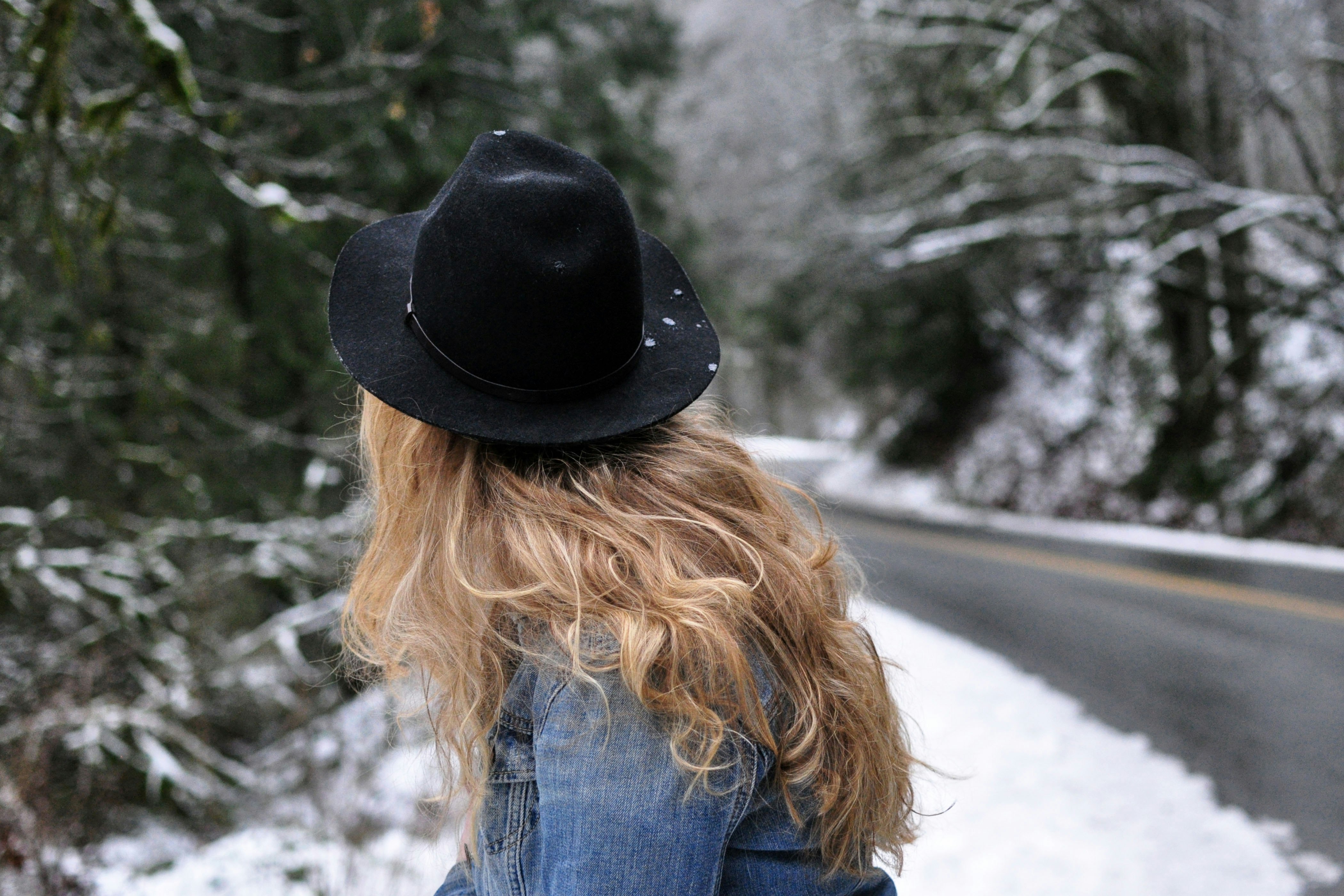 woman wearing blue denim jacket and black cowboy hat near road