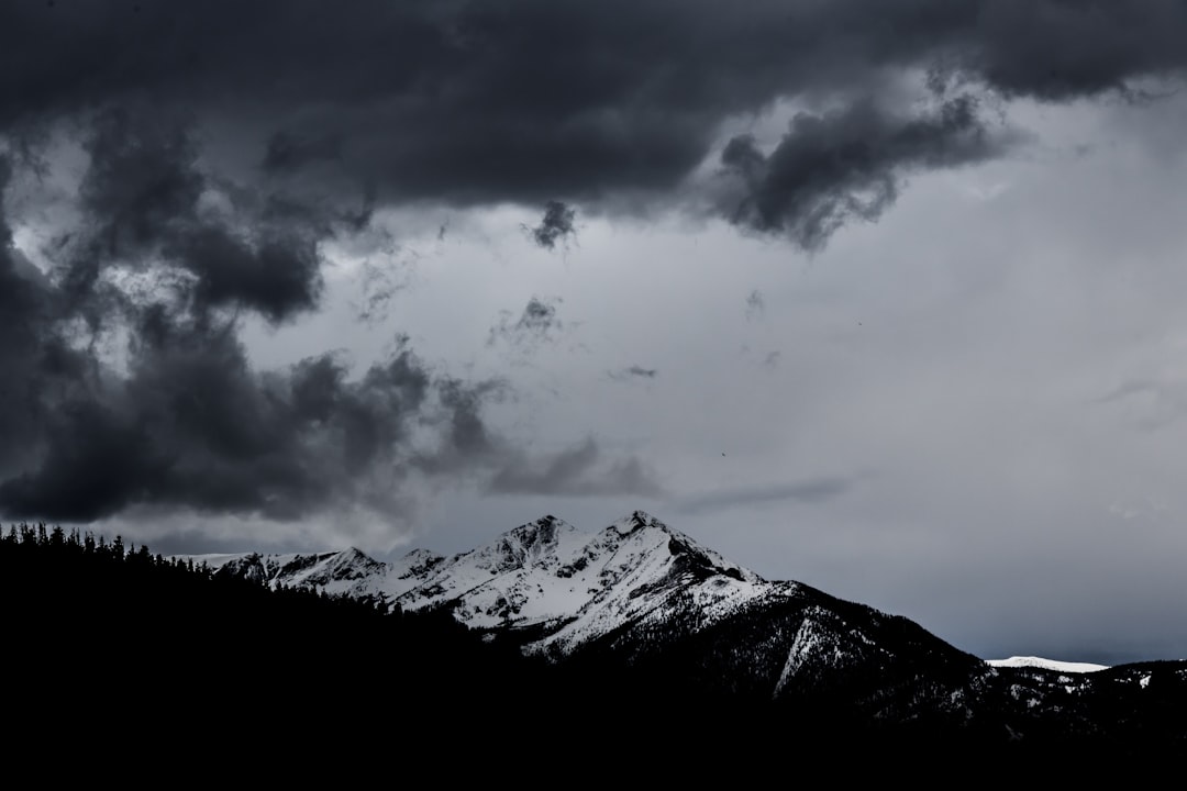 snowy mountain under dramatic clouds