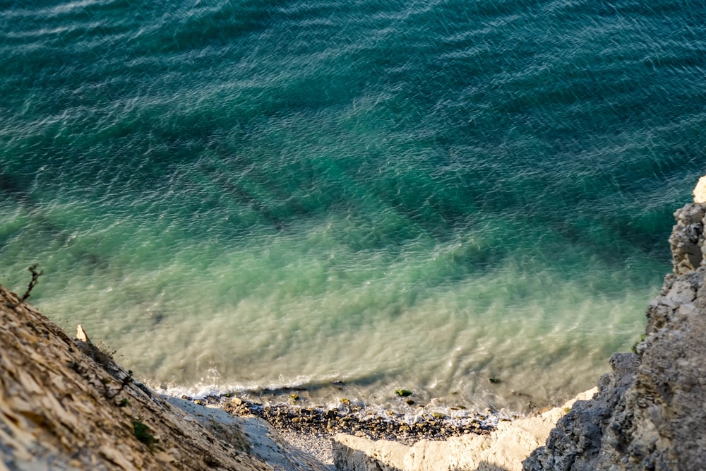 aerial photo of sea shore near rocky mountain during daytime