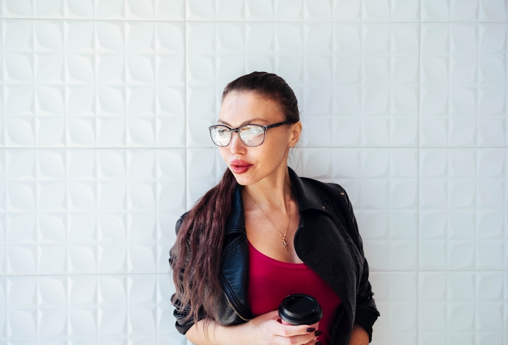 Femme en veste noire debout près du mur