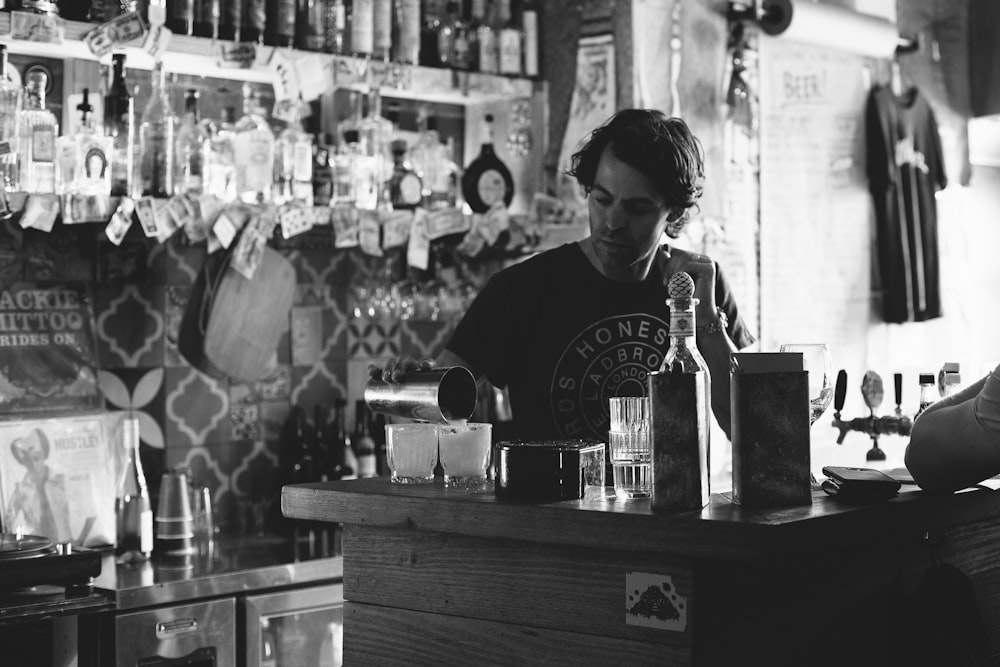 man standing while pouring liquid on cup inside bar