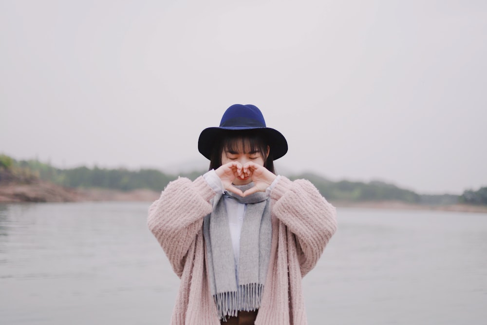 woman forming heart by hand near water