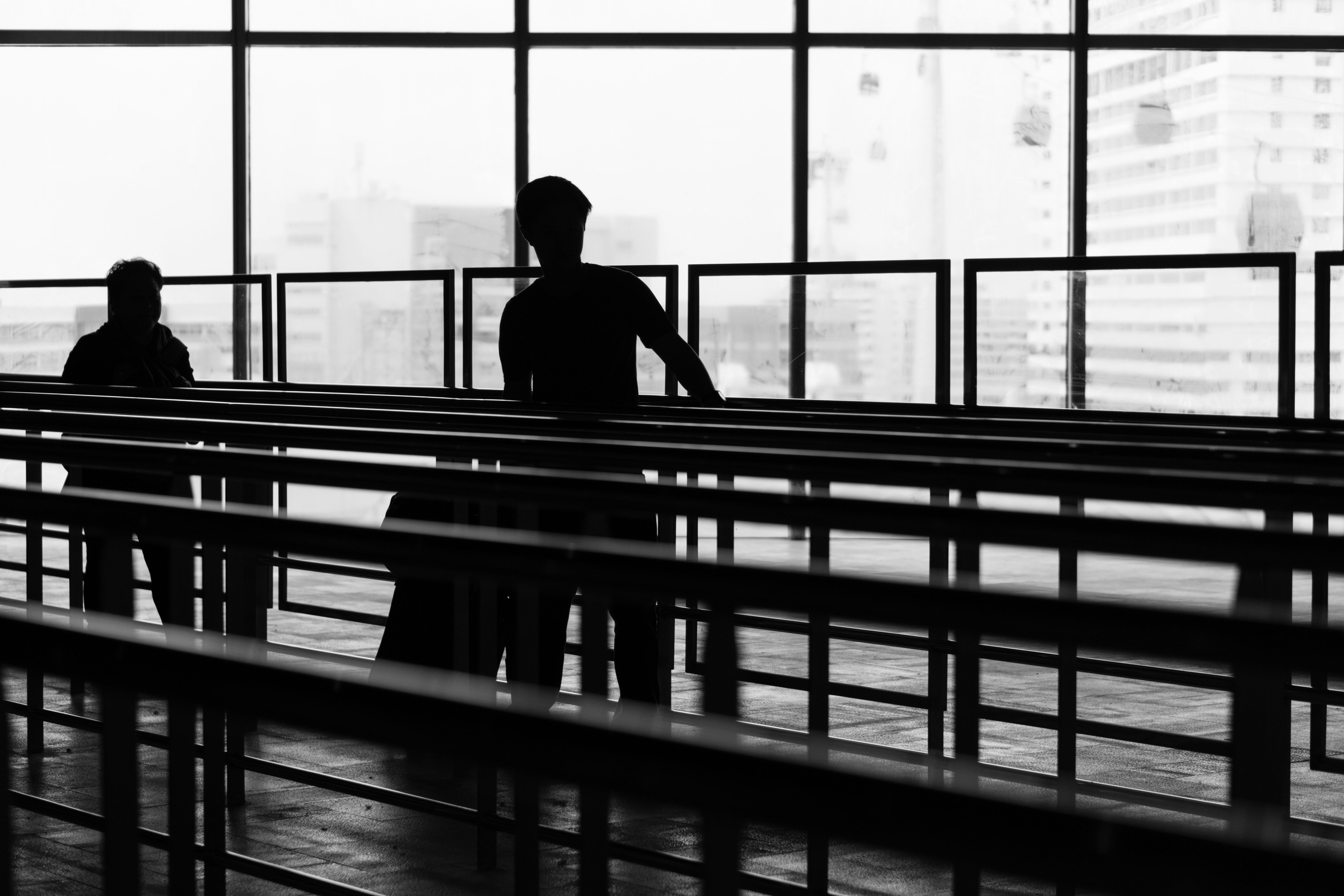 silhouette of two person inside glass building, Person going through an empty queue