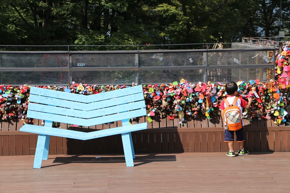 toddler standing near blue wooden bench