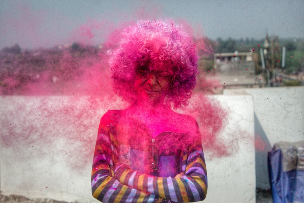 Person, die tagsüber rosa Spray auf die Haare sprüht