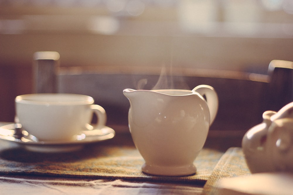 white ceramic teapot beside cup and saucer