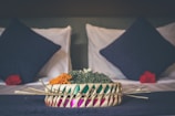Close-up of a comfortable bed with colorful cushions in a Varanasi BnB room.