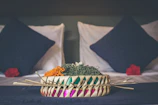 A woven decorative basket filled with colorful throws and pillows.