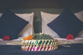 A woven decorative basket filled with vibrant throws and pillows.