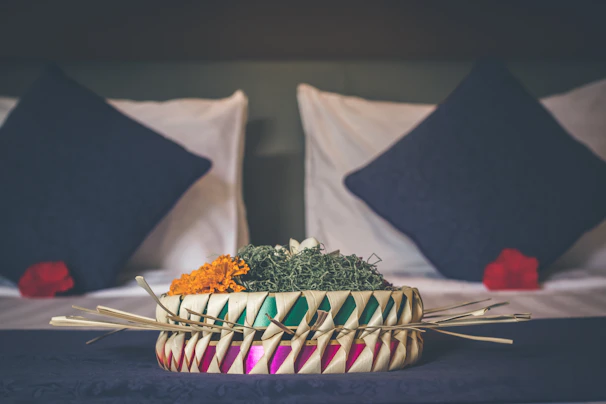 A decorative basket filled with vibrant throw blankets and pillows.