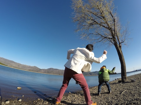 Children playing and skipping stones along the lakeside beach.