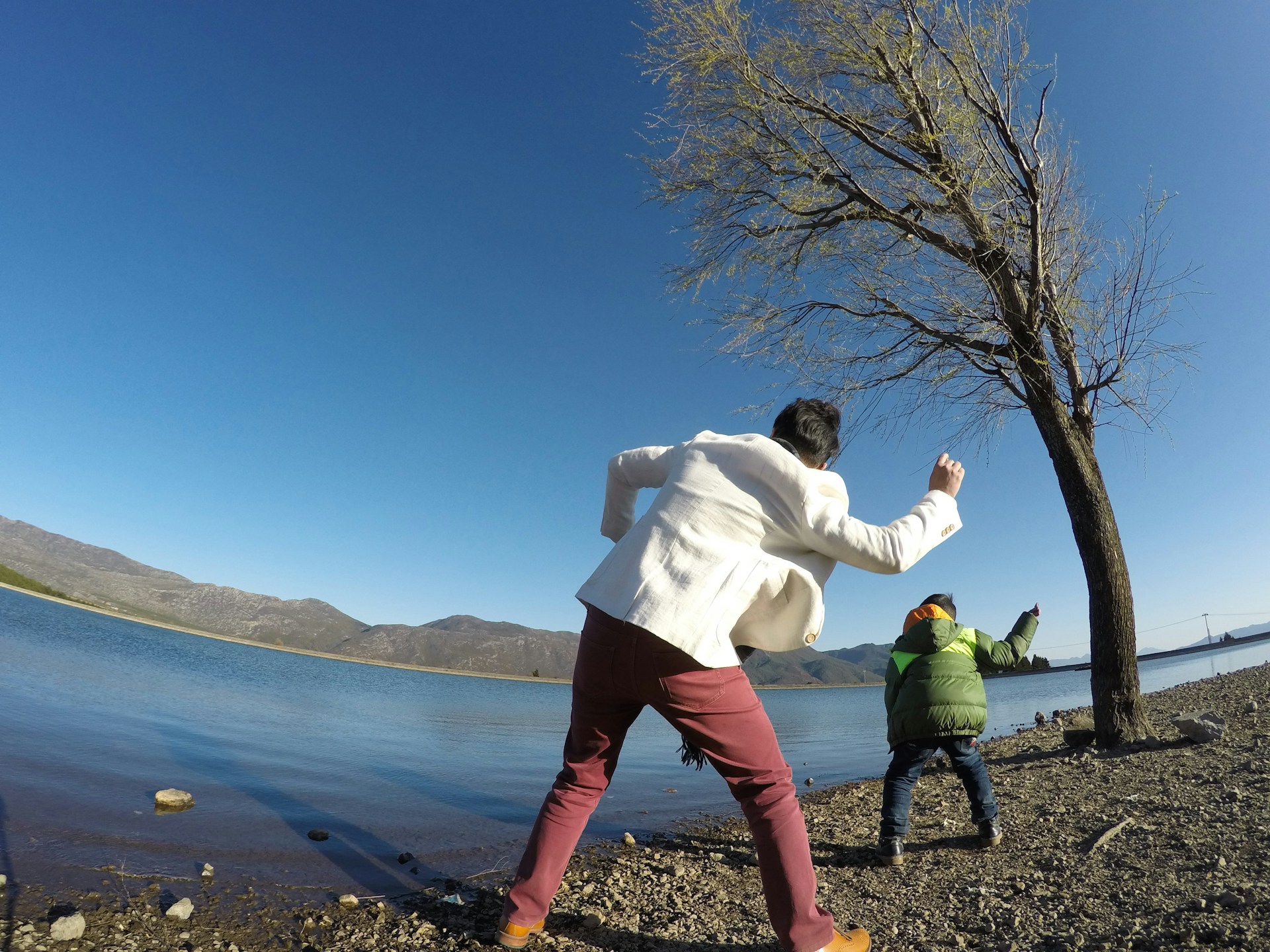 Children laughing as they skip stones across a clear mountain creek surrounded by autumn leaves on a crisp Colorado afternoon.