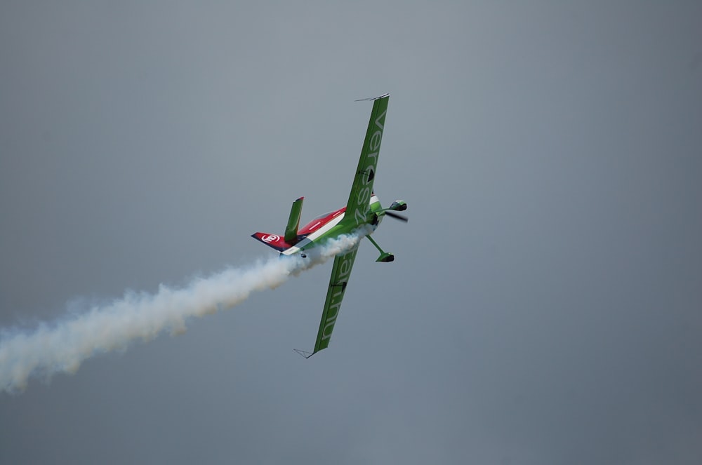 green monoplane flying in the sky