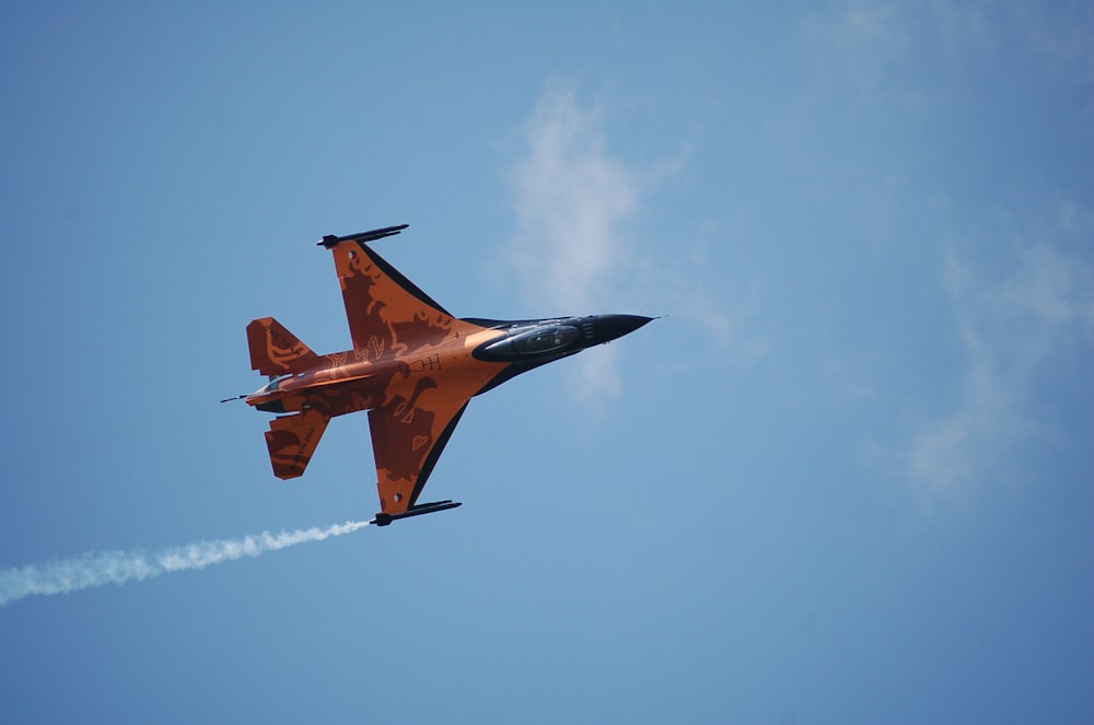 Roter und schwarzer Kampfjet am bewölkten Himmel