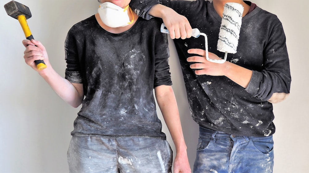 man and woman holding sledgehammer and paint roller