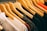 A row of wooden hangers holds a variety of clothes, dominated by white, black, and orange garments. The clothes appear to be neatly arranged in a sequence, suggesting a retail display or a well-organized closet.