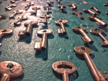 Close-up of vintage brass keys resting on a smooth wooden tray bathed in soft light.