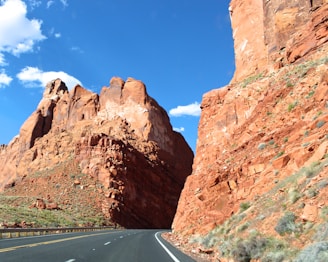 curved road in between brown rock cliffs