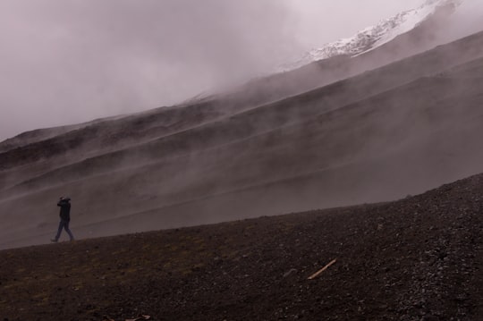 person walking on gravel with grey smoke in Cotopaxi Ecuador