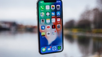 silver iPhone X floating over open palm