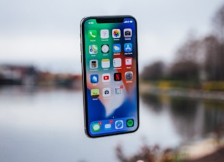 silver iPhone X floating over open palm