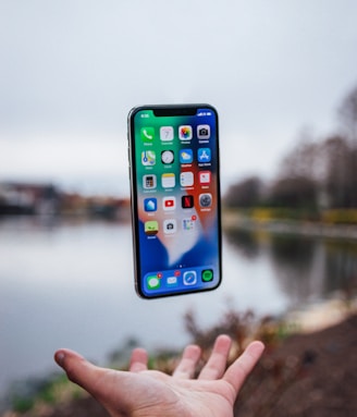 silver iPhone X floating over open palm