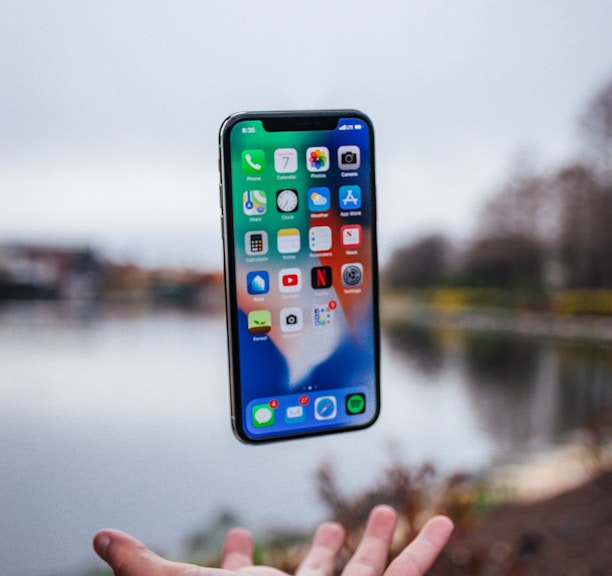 silver iPhone X floating over open palm