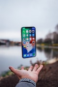 silver iPhone X floating over open palm