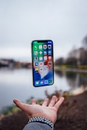 silver iPhone X floating over open palm