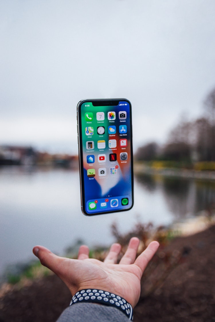 An iphone being tossed into the air with a hand underneath.