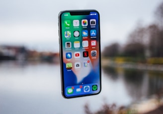 silver iPhone X floating over open palm