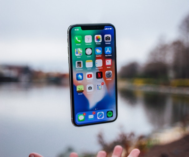 silver iPhone X floating over open palm