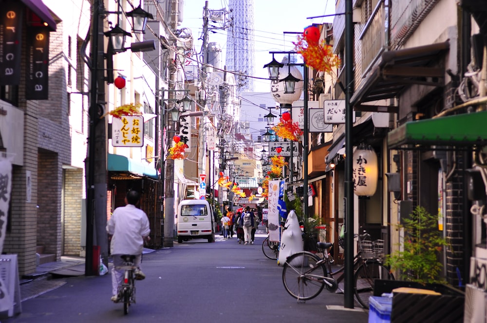 person riding on bicycle on road in between building