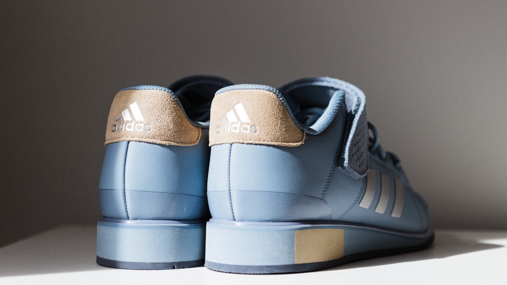 Paar blau-braune adidas Low-Top-Sneaker auf weißem Brett