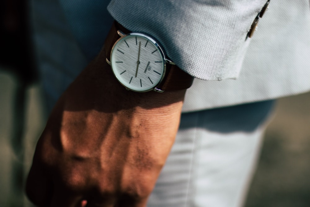 man wearing round analog watch and gray suit jacket