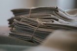A stack of neatly folded fabric pieces, tied together with a brown string. The fabric appears textured, possibly made of a natural material like linen or cotton.