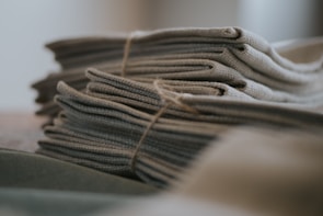 A stack of neatly folded fabric pieces, tied together with a brown string. The fabric appears textured, possibly made of a natural material like linen or cotton.