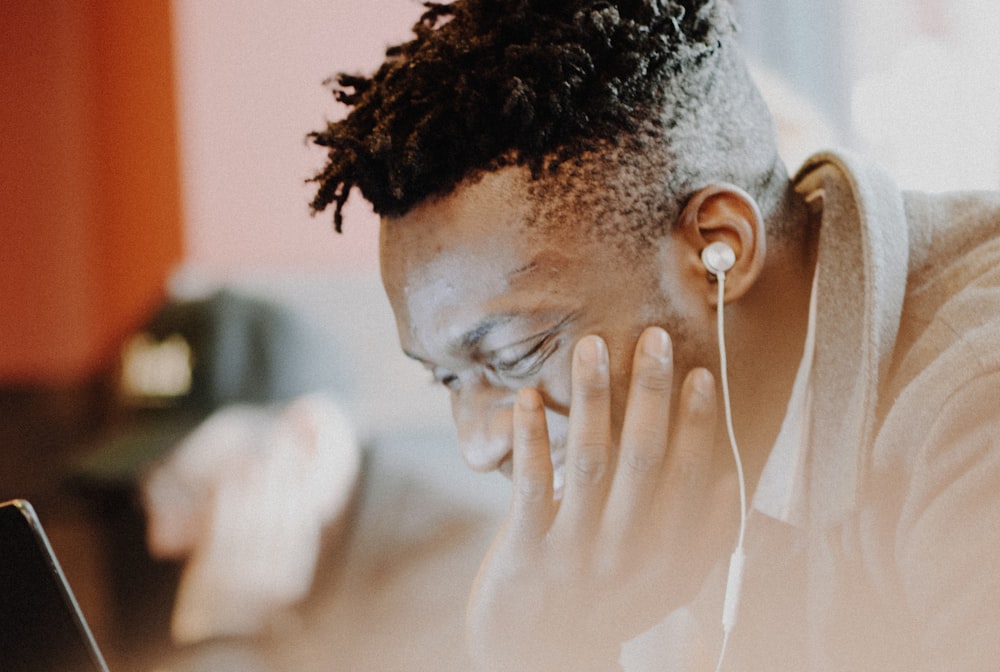 man wearing earphones laughing in front of monitor