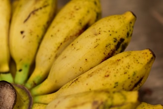 Close-up of ripe yellow bananas and golden mangos arranged on a rustic wooden table.