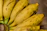 Close-up of a bunch of bright yellow Cavendish bananas with smooth peel on a wooden table.