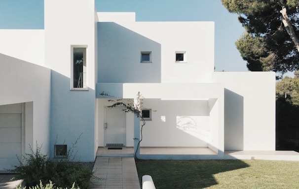 white concrete house near green tree during daytime