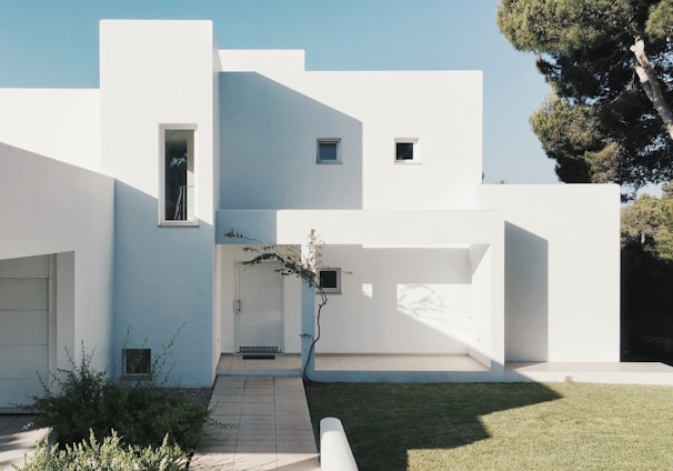 white concrete house near green tree during daytime