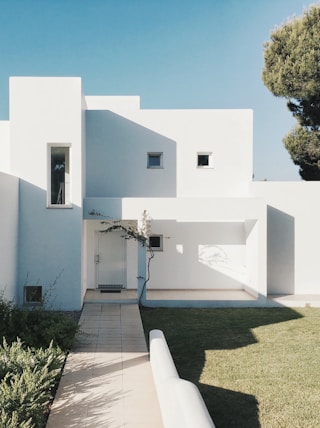 white concrete house near green tree during daytime