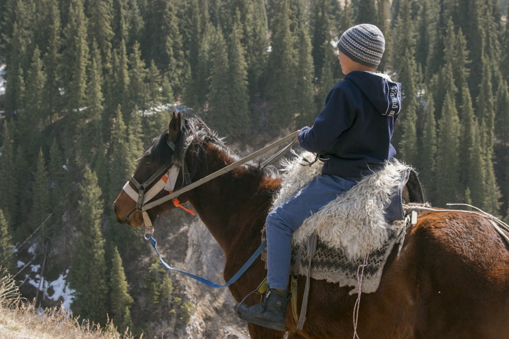 Teenager riding a horse in the mountains.