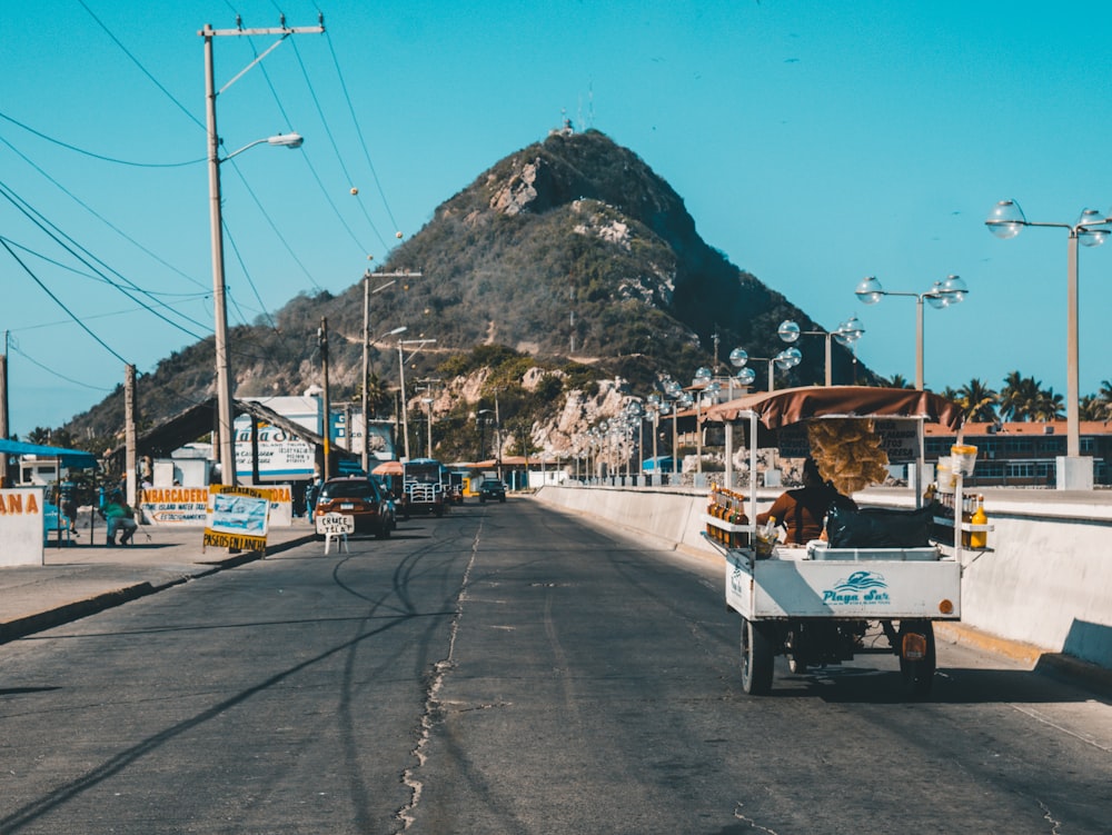 rickshaw auto blanco en la conducción en la carretera asfaltada hacia la montaña verde