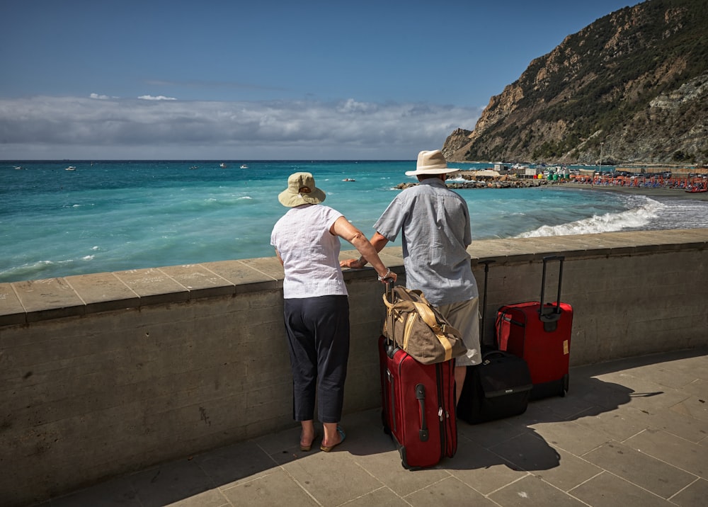 homme et femme debout à côté de la digue en béton regardant la plage