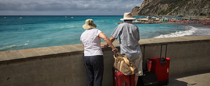 man and woman standing beside concrete seawall looking at beach