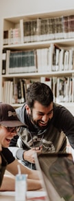 three men laughing while looking in the laptop inside room