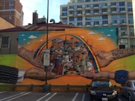 Close-up of hands working together on a colorful community mural.