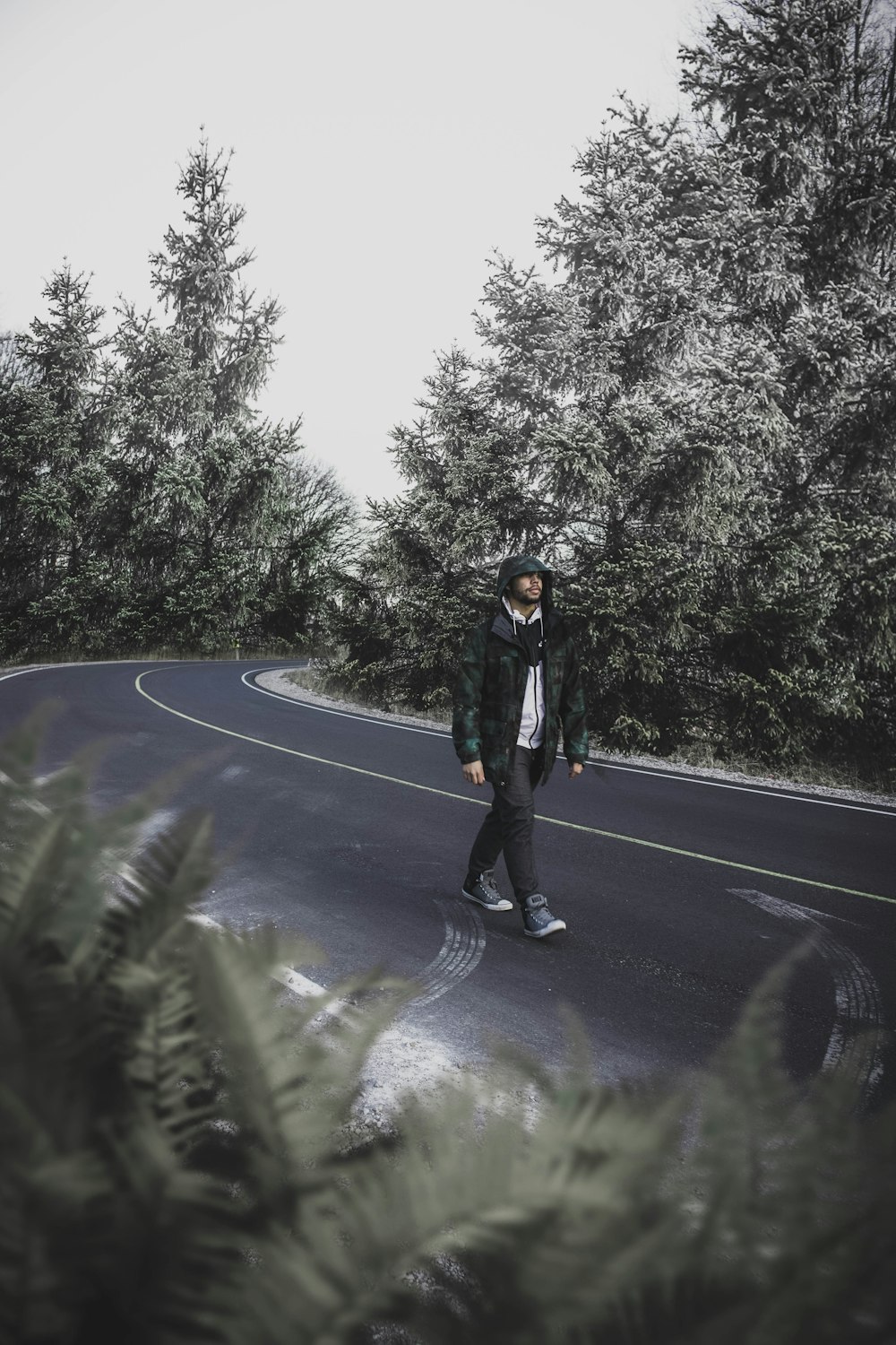 man walking on street between trees